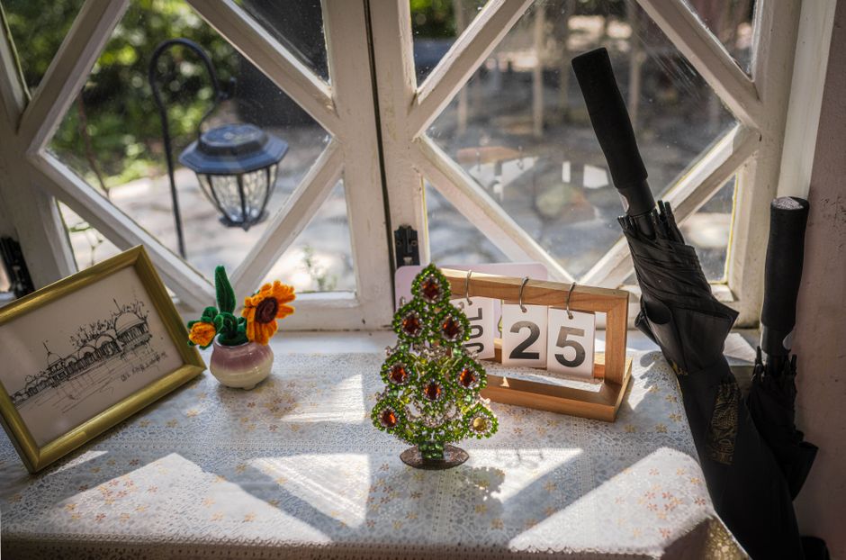 Charming table by window with mini Christmas tree, calendar date, and artistic decor.